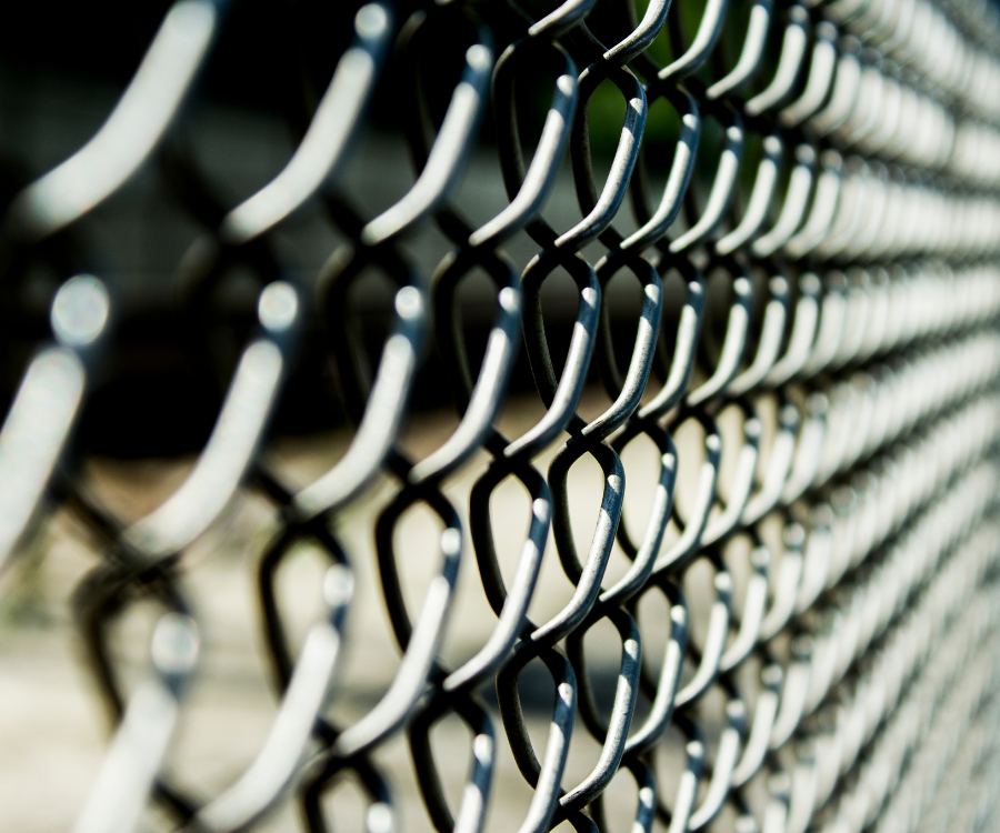 Zbliżenie na metalową siatkę ogrodzeniową z drutu stalowego, rozciągniętą wzdłuż.